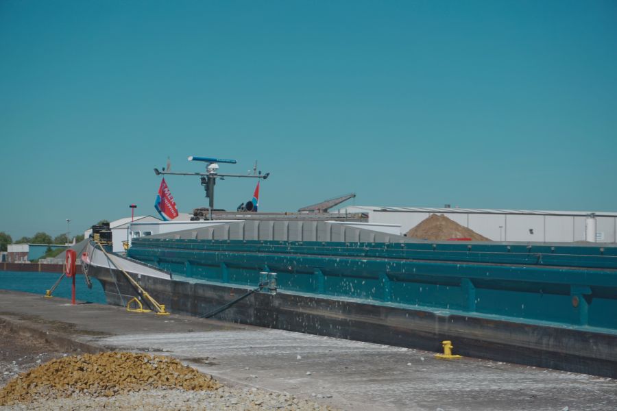 Binnenschiff beim Umschlag von mineralischen Baustoffen am Hafenstandort in Dortmund für trimodale Logistik im Infrastrukturbau.