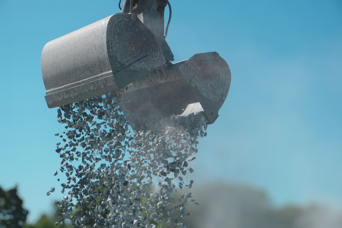 Schotter wird mit einem Greifer verladen und als Schüttgut für Infrastrukturprojekte im Straßen- und Tiefbau eingesetzt.